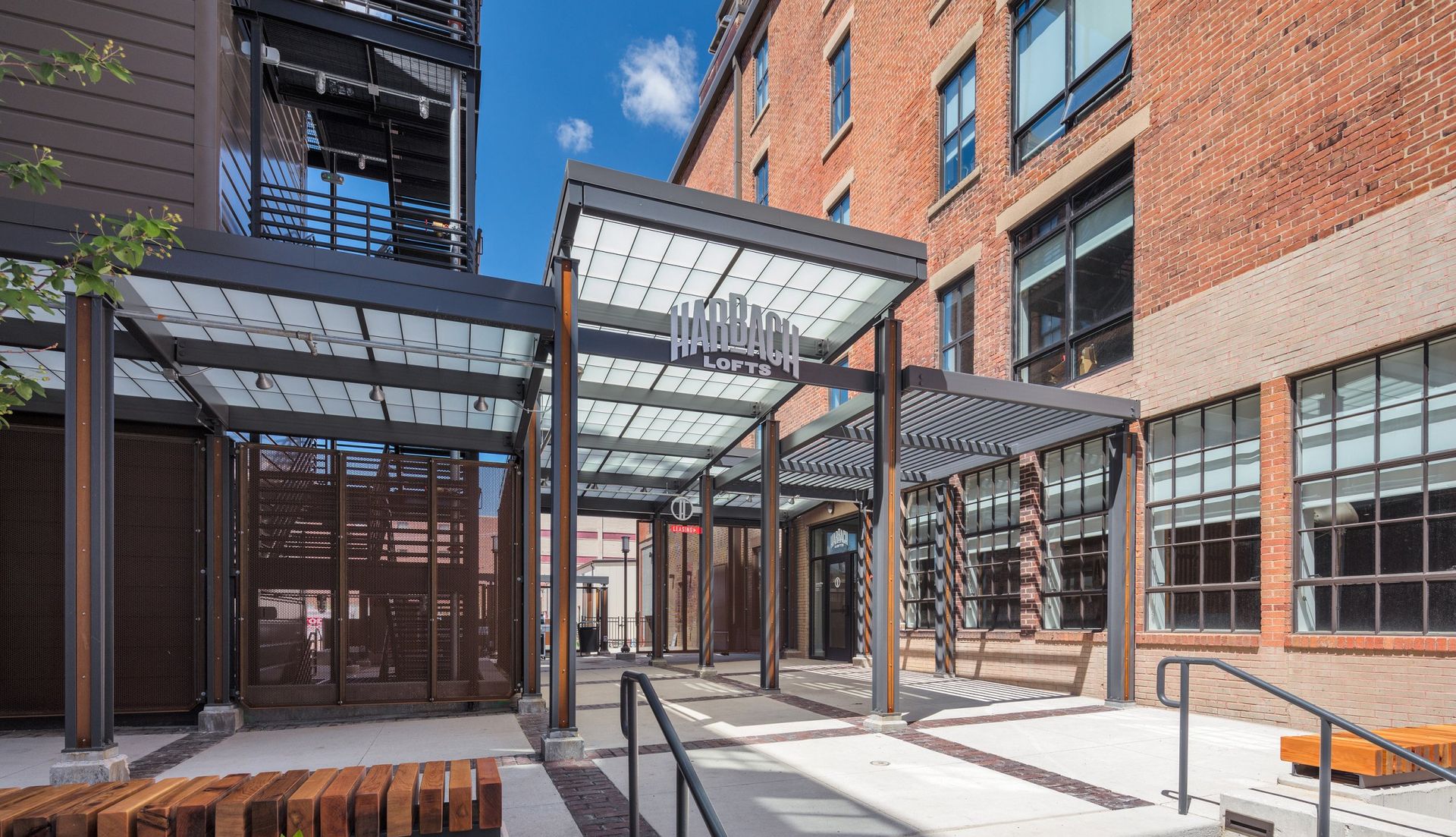 The dimensional Harbach Lofts sign over the courtyard entrance, with the original 1906 brick building behind it