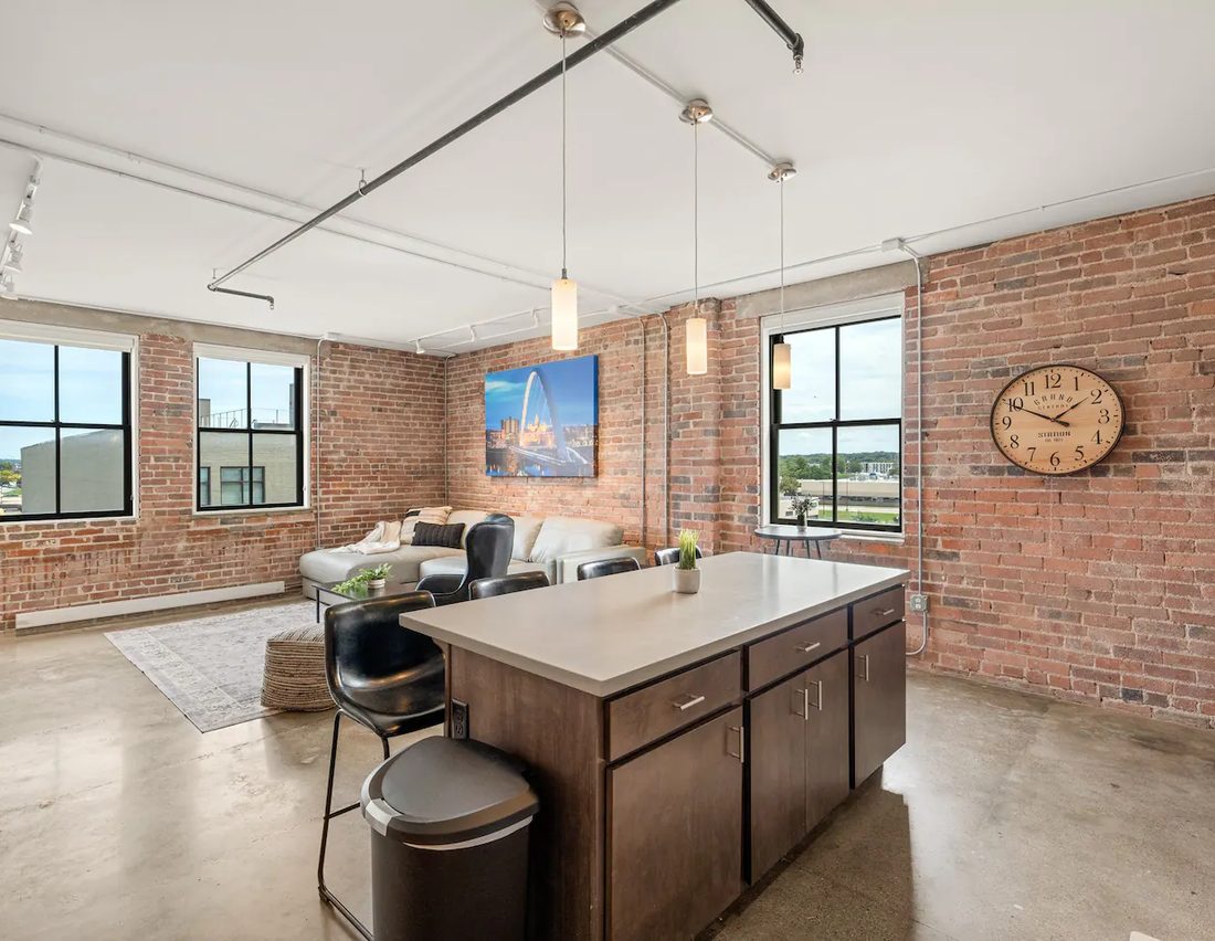 A Harbach Lofts kitchen and living space with original brick, factory windows, and skyline art